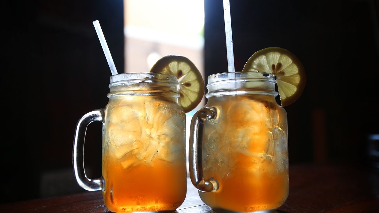Two mason jar mugs filled with sweet tea, ice and lemon slice garnishes sit atop a bar table.