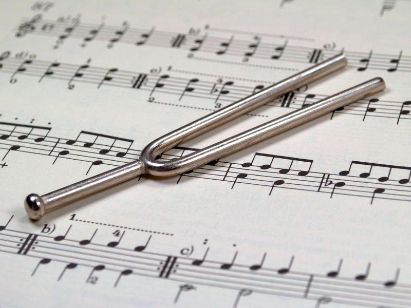 Image of a tuning fork atop a page from a musical score.