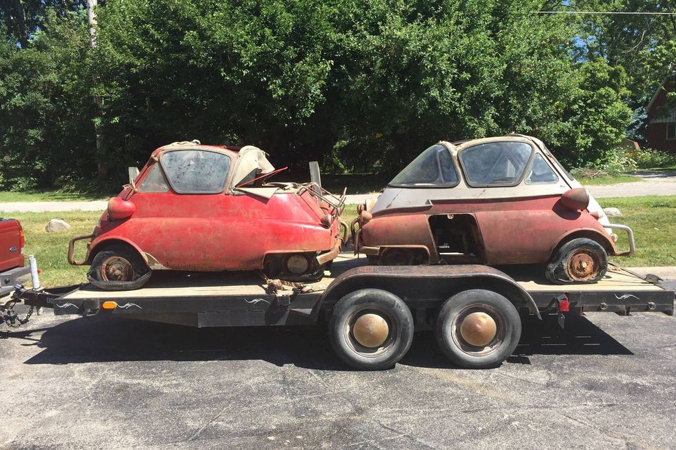 A pair of unrestored bubble-window BMW Isettas found in a farmer's field, loaded on a trailer