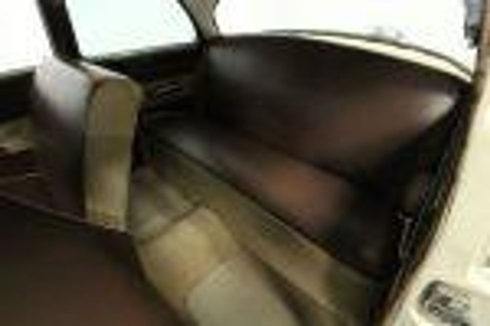 Back seat of a 1953 Ford upholstered in brown and cream.