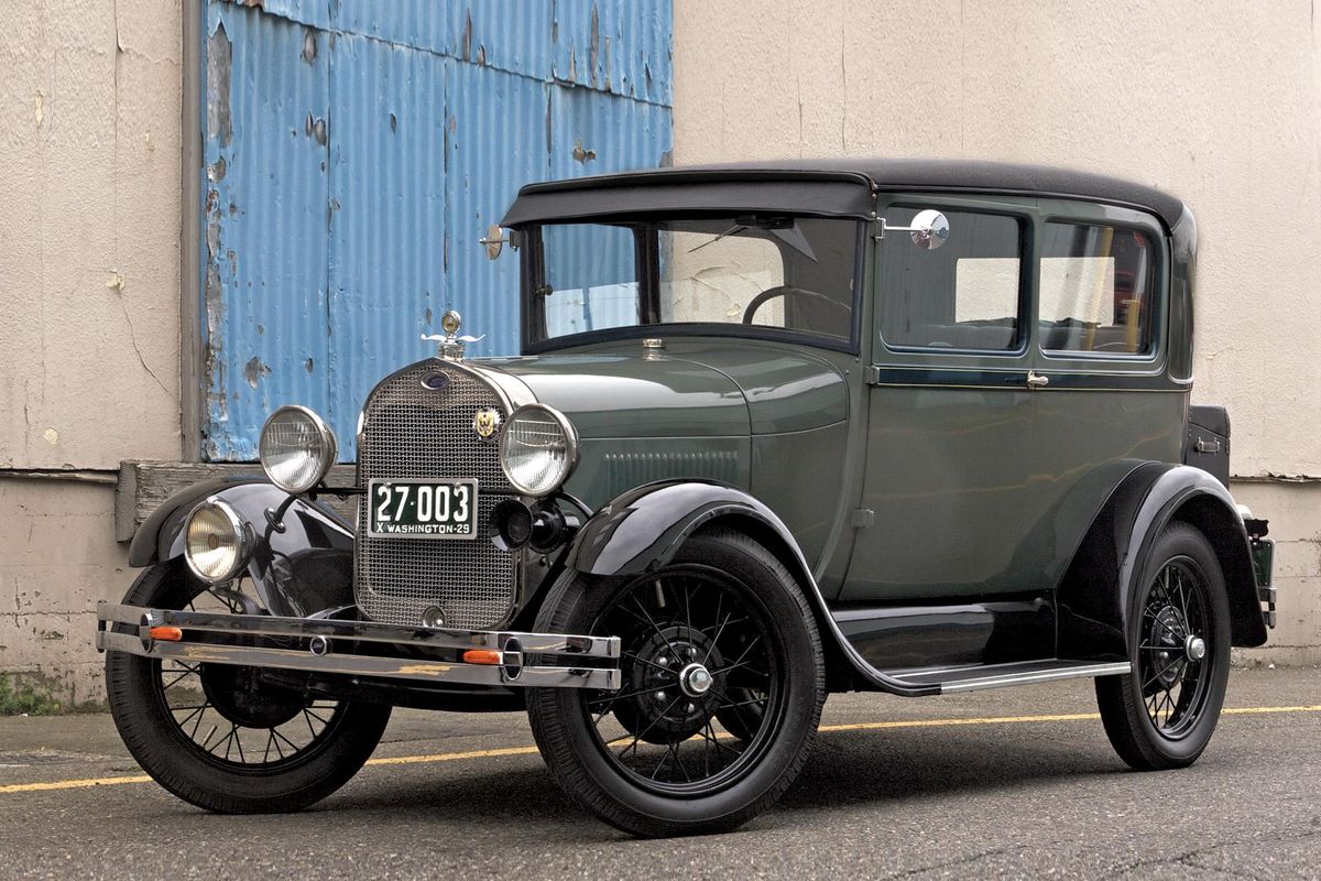 Color image of a 1929 Ford Model A Tudor, parked in front of a building, front 3/4 position.