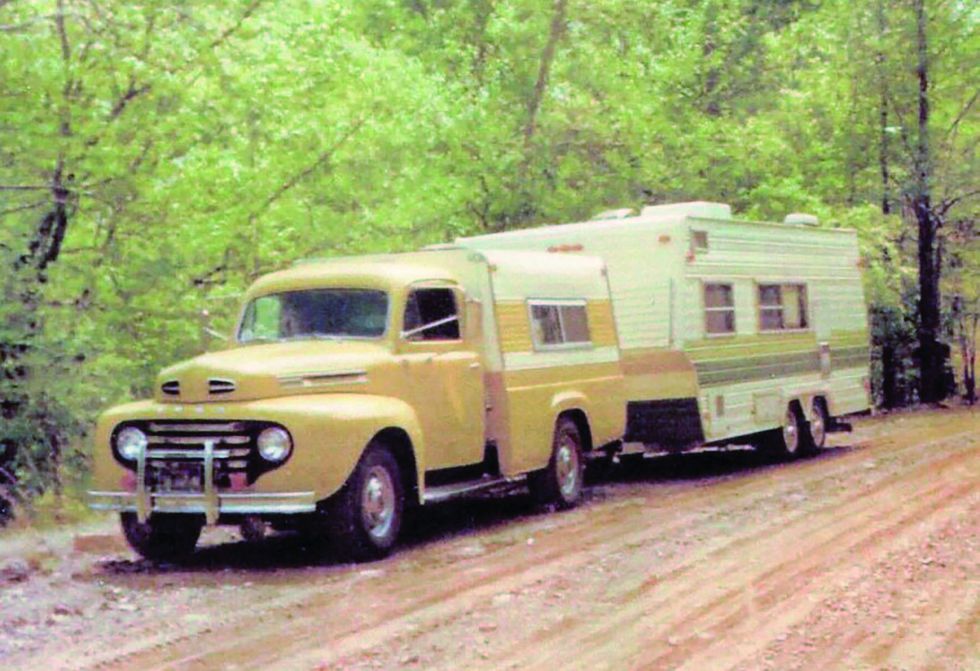 Color image of a 1950 Ford F-3 hauling a trailer/camper, front 3/4 position.