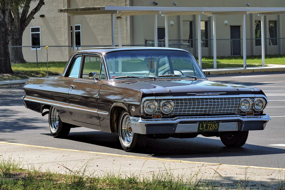 Color image of a 1963 Chevrolet Bel Air 409 parked in front of a house, front 3/4 position. 