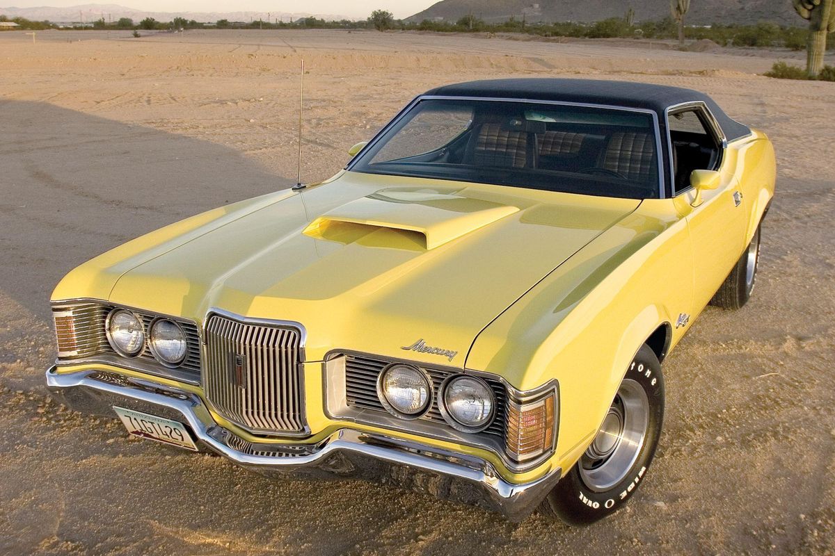 Color image of a 1971 Mercury Cougar 429CJ parked on sand in the desert, front 3/4 position.