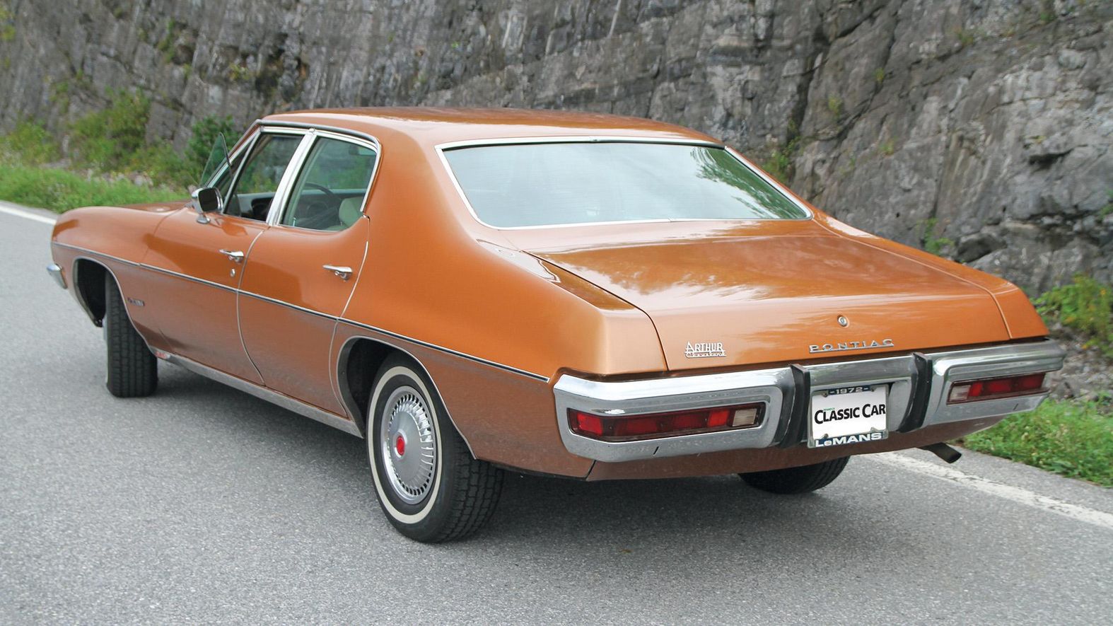 Color image of a 1972 Pontiac Le Mans parked in front of a mountain and rocks, rear 3/4 position.