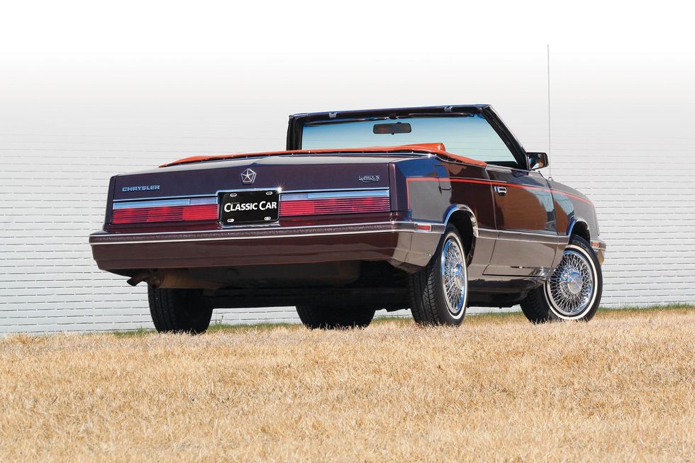 Color image of a 1982 Chrysler LeBaron Medallion Mark Cross edition car parked in front of a wall, rear 3/4 position, top down.