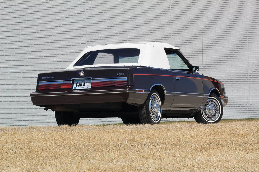Color image of a 1982 Chrysler LeBaron Medallion Mark Cross edition car parked in front of a wall, rear 3/4 position, top up.
