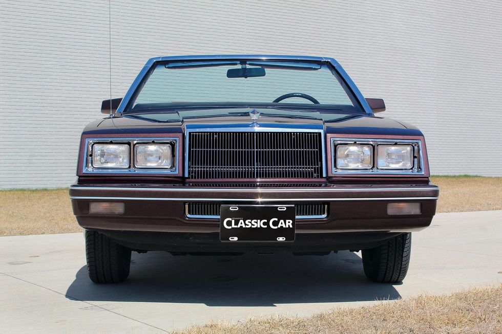 Color image of a 1982 Chrysler LeBaron Medallion Mark Cross Edition parked in front of a wall, head-on position.